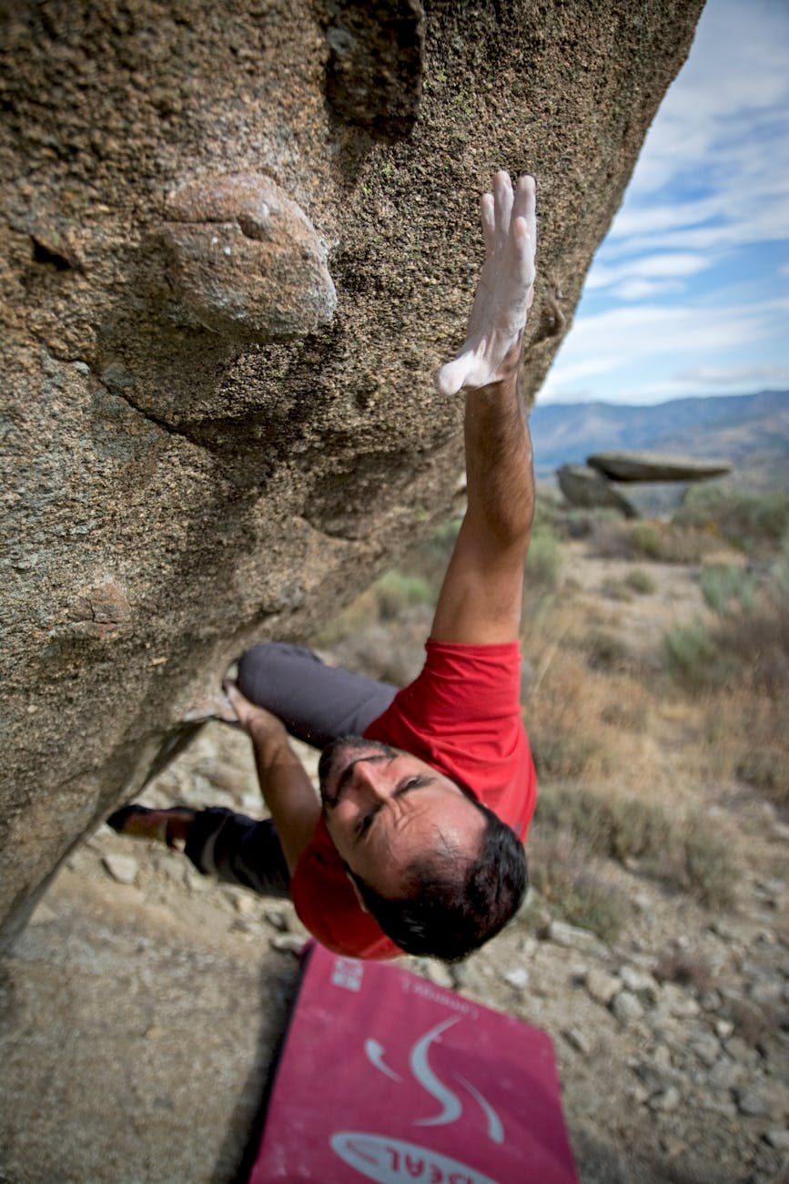man climbing on gray concrete peak at daytime