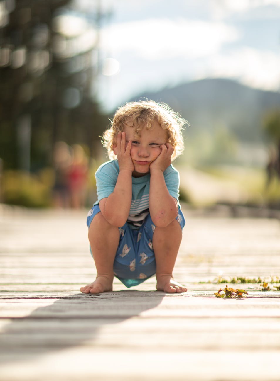 a young girl in blue shirt sitting on the ground